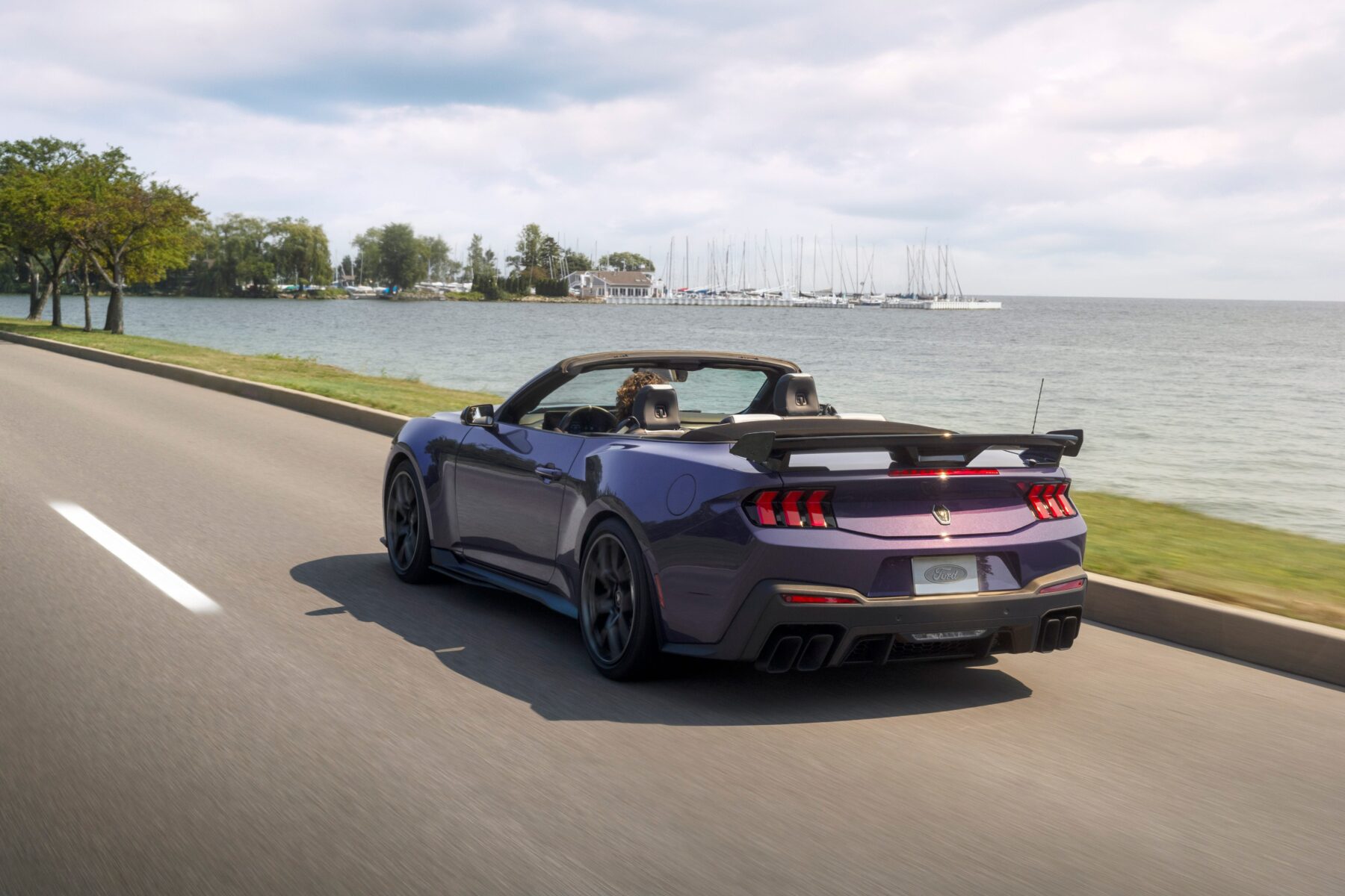 Lila Ford Mustang Dark Horse SC Convertible von hinten auf einer Straße am Wasser